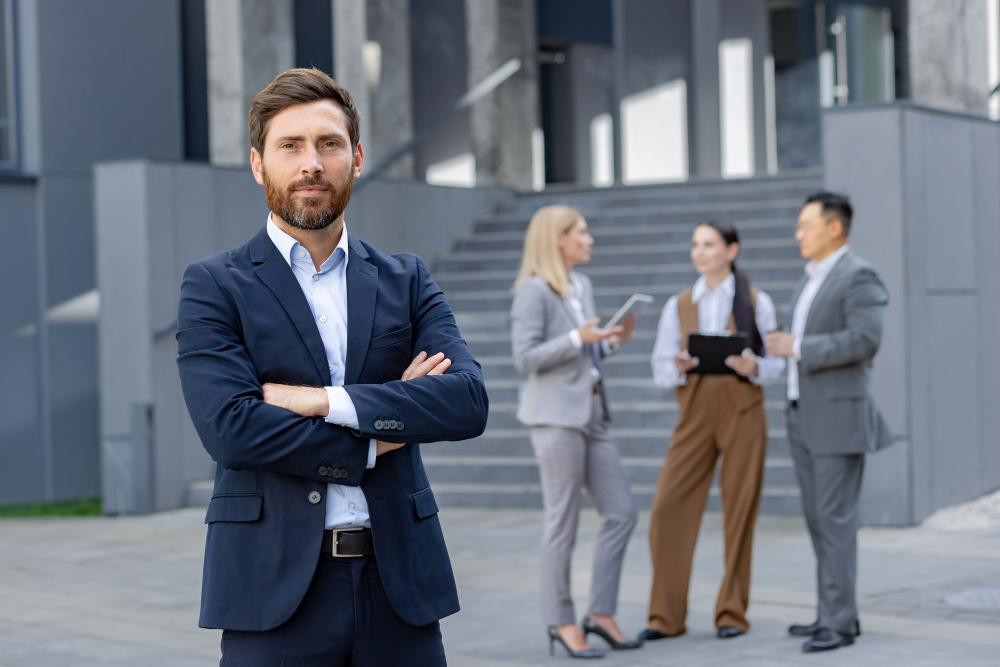 Confident businessman outdoors with colleagues in background